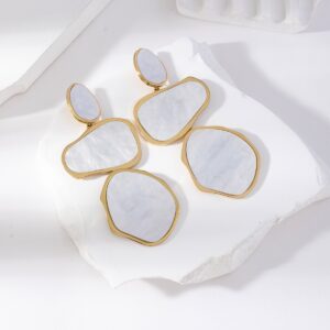 Boucles d’oreilles pendantes en acier inoxydable doré, ornées de segments irréguliers marbrés blanc nacré, présentées sur fond blanc texturé – bijou moderne et artistique pour femme.