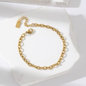 Bracelet gourmette en acier inoxydable doré avec chaîne forçat et fermoir ajustable, présenté sur fond blanc texturé – bijou minimaliste et élégant pour femme.