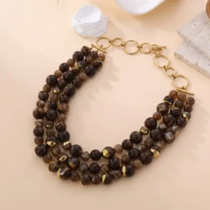 Collier multi-rangs Laura avec perles brunes et fumées, accents dorés et fermoir en anneaux, bijou élégant sur fond beige