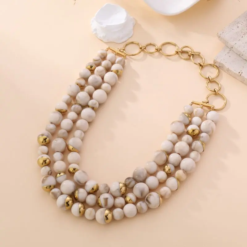 "Collier multi-rangs Laura avec perles marbrées crème et accents dorés, fermoir en anneaux, bijou élégant sur fond beige