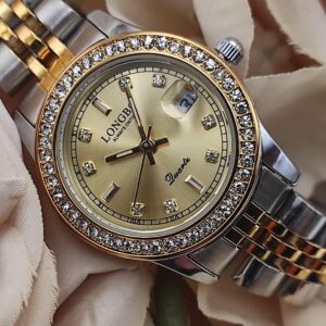 Montre LONGBO à cadran doré avec bracelet bicolore argent et or, lunette sertie de cristaux, date avec loupe à 3h, posée sur un fond de fleurs beige