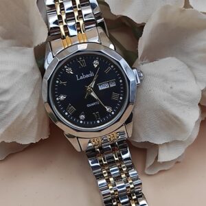 Montre Labaoli à cadran noir avec chiffres dorés stylisés, affichage jour et date à 3h, bracelet métallique bicolore argent et or, posée sur un fond floral beige.